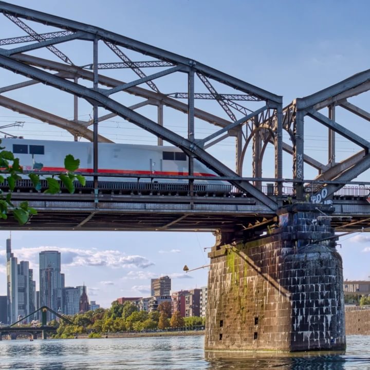 ICE fährt durch die Fachwerk-Bogenportale der Deutschherrnbrücke, Skyline im Hintergrund, 2024